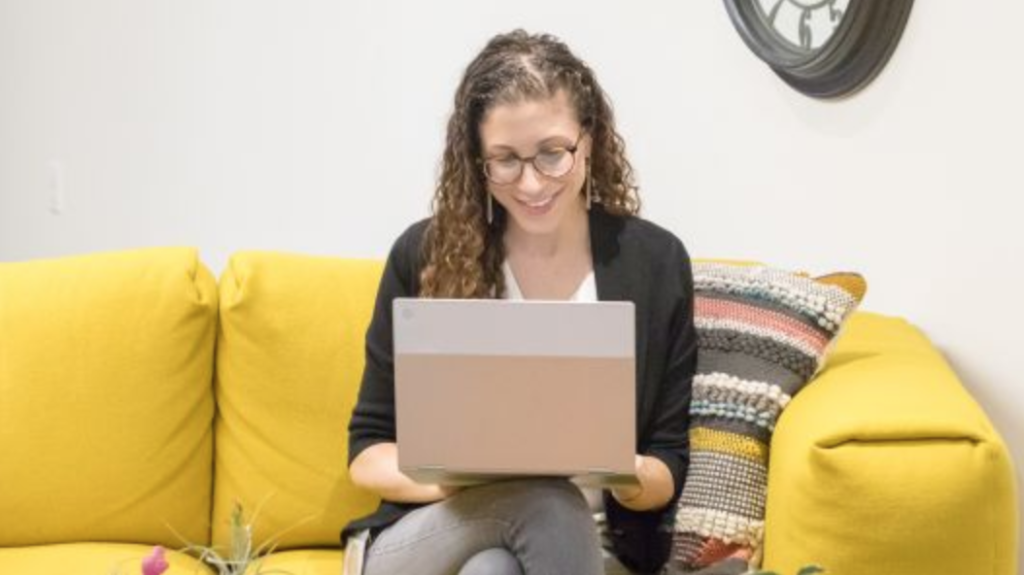 Lauran Allen sitting on a couch working on a laptop