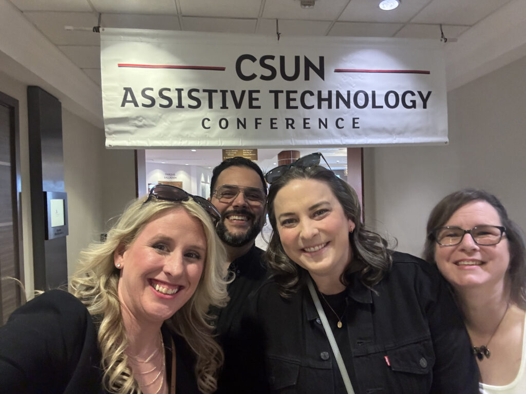 Teach Access team standing with a CSUN Assistive Technology Conference banner overhead.