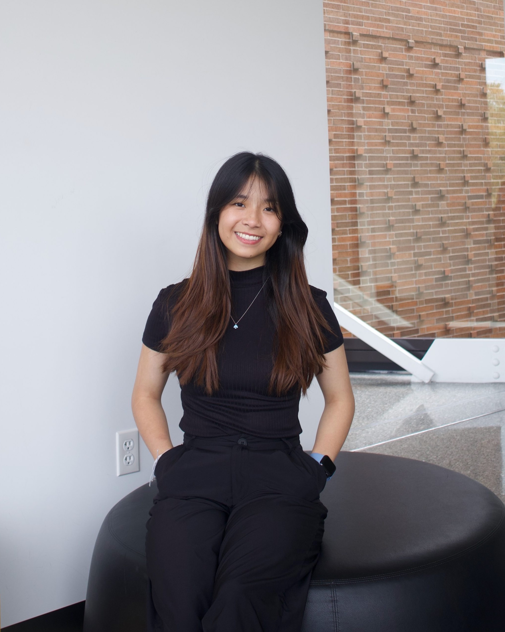 A professional headshot of Sherrye Zhong, a woman with black hair styled neatly, wearing a black top and black pants. She is smiling at the camera with a neutral background.