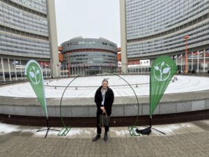 Kate standing between two green ZeroCon flags outside a conference center